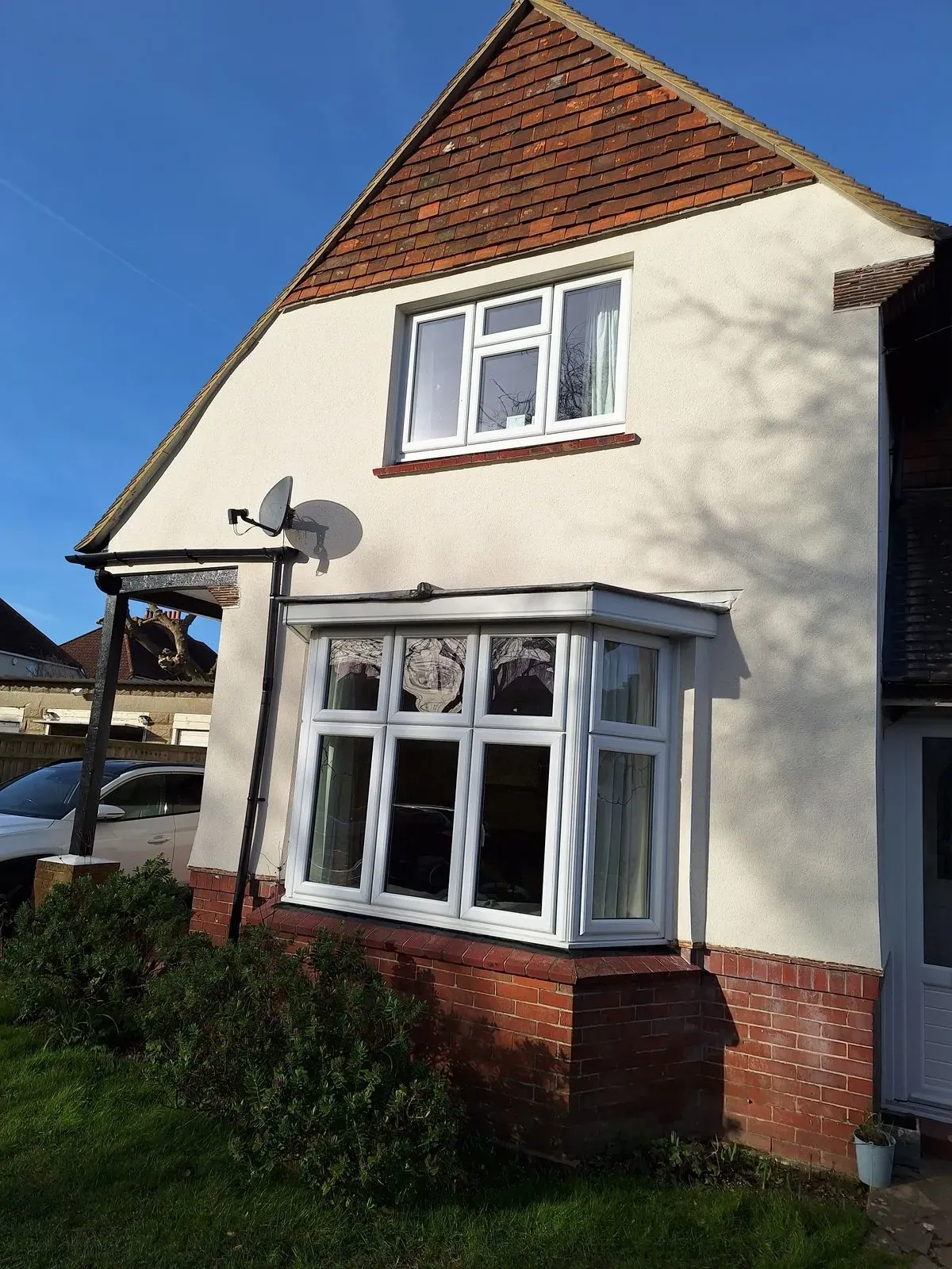 Cream-rendered house exterior with a bay window and tiled roof.