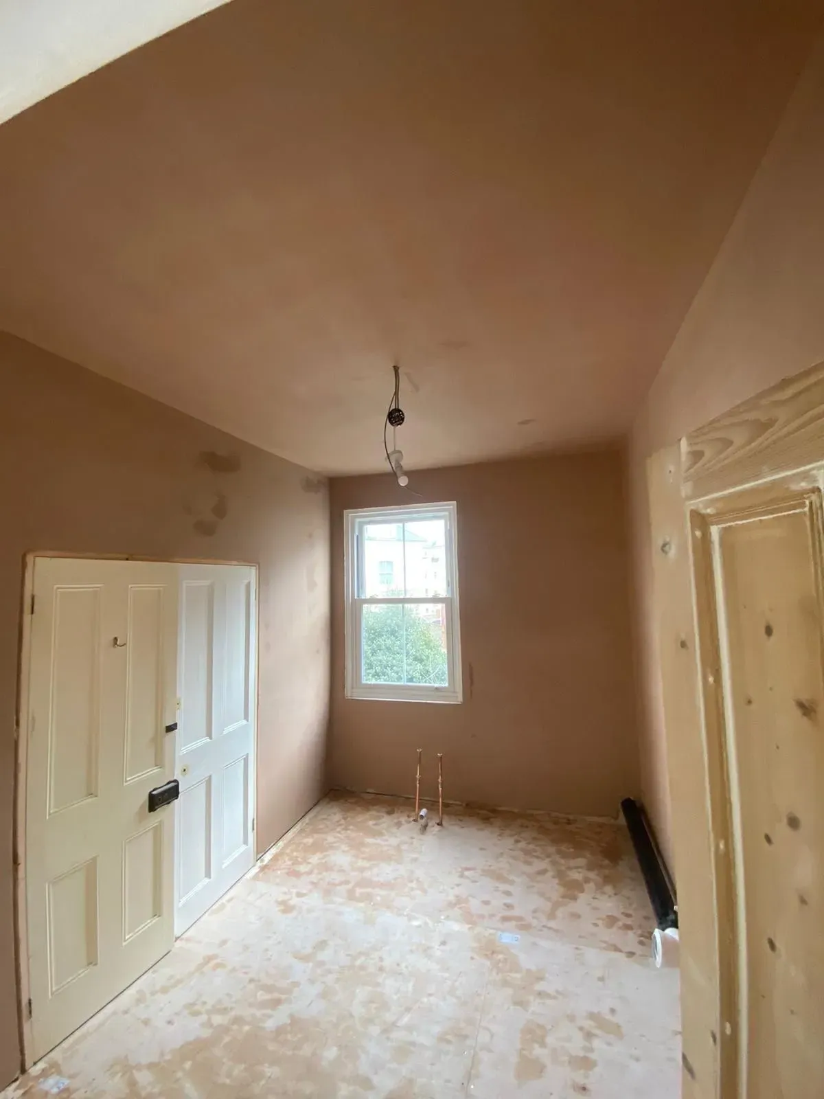 Freshly plastered room with a window and an internal doorway.