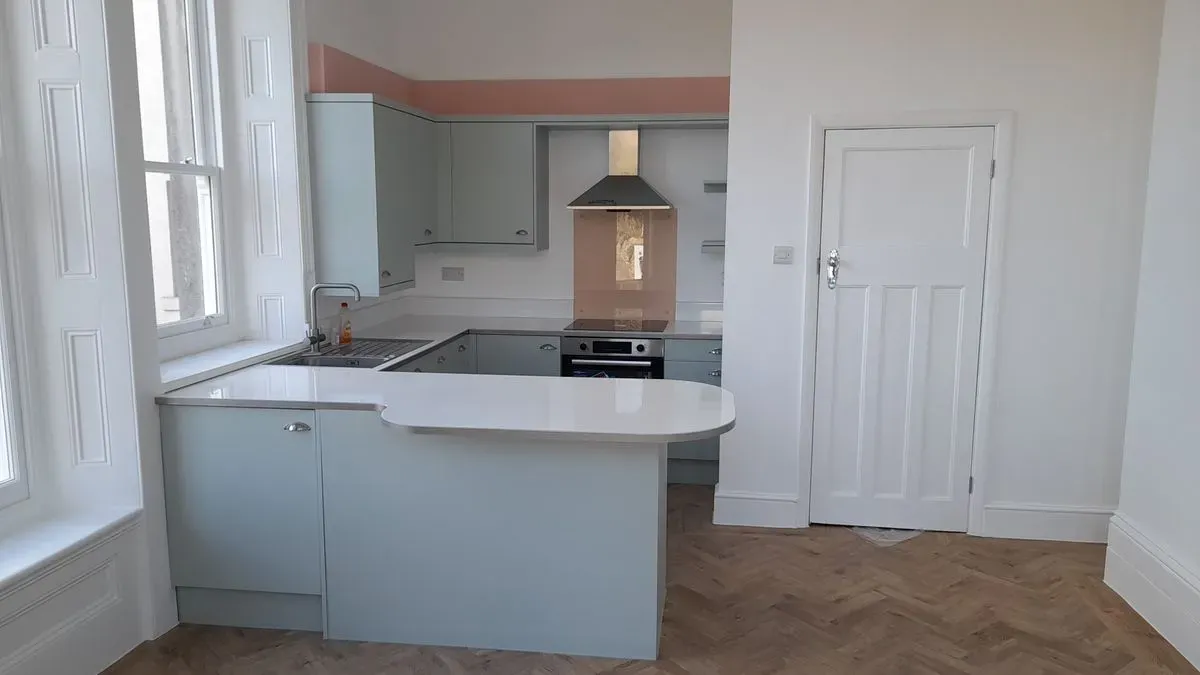 Kitchen with white cabinets, a peninsula and a stainless steel extractor hood.