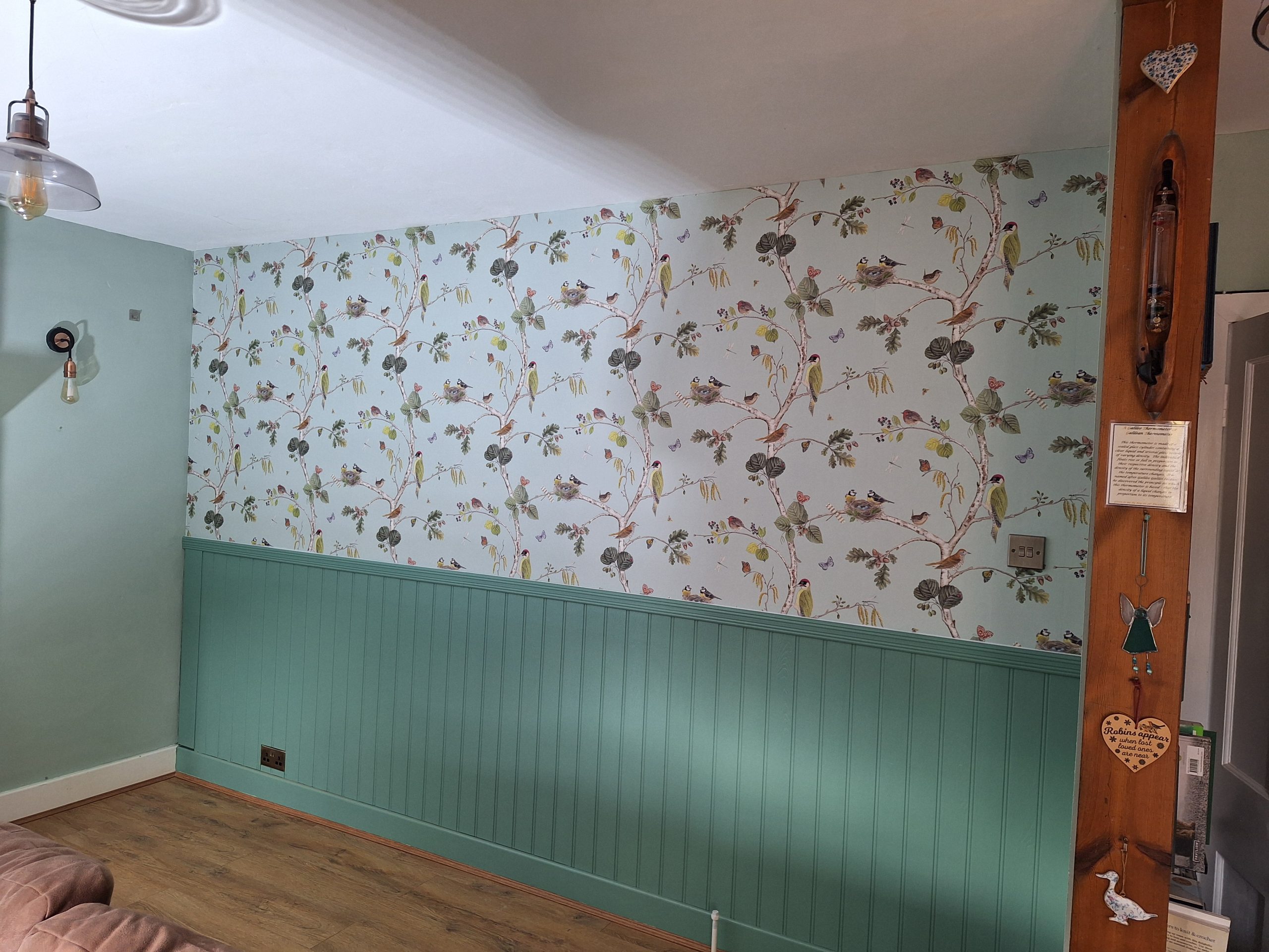 Patterned wallpaper above painted wall panelling.