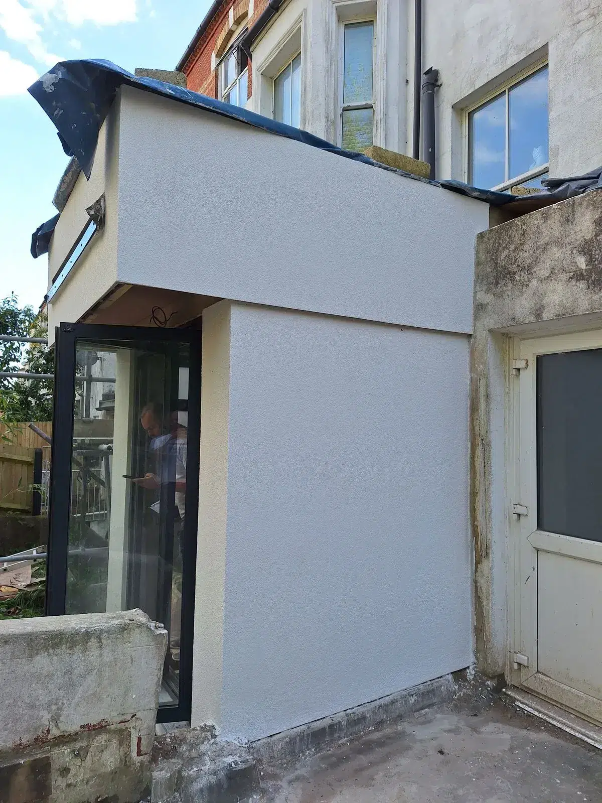 White-rendered extension with dark-framed doors and windows.